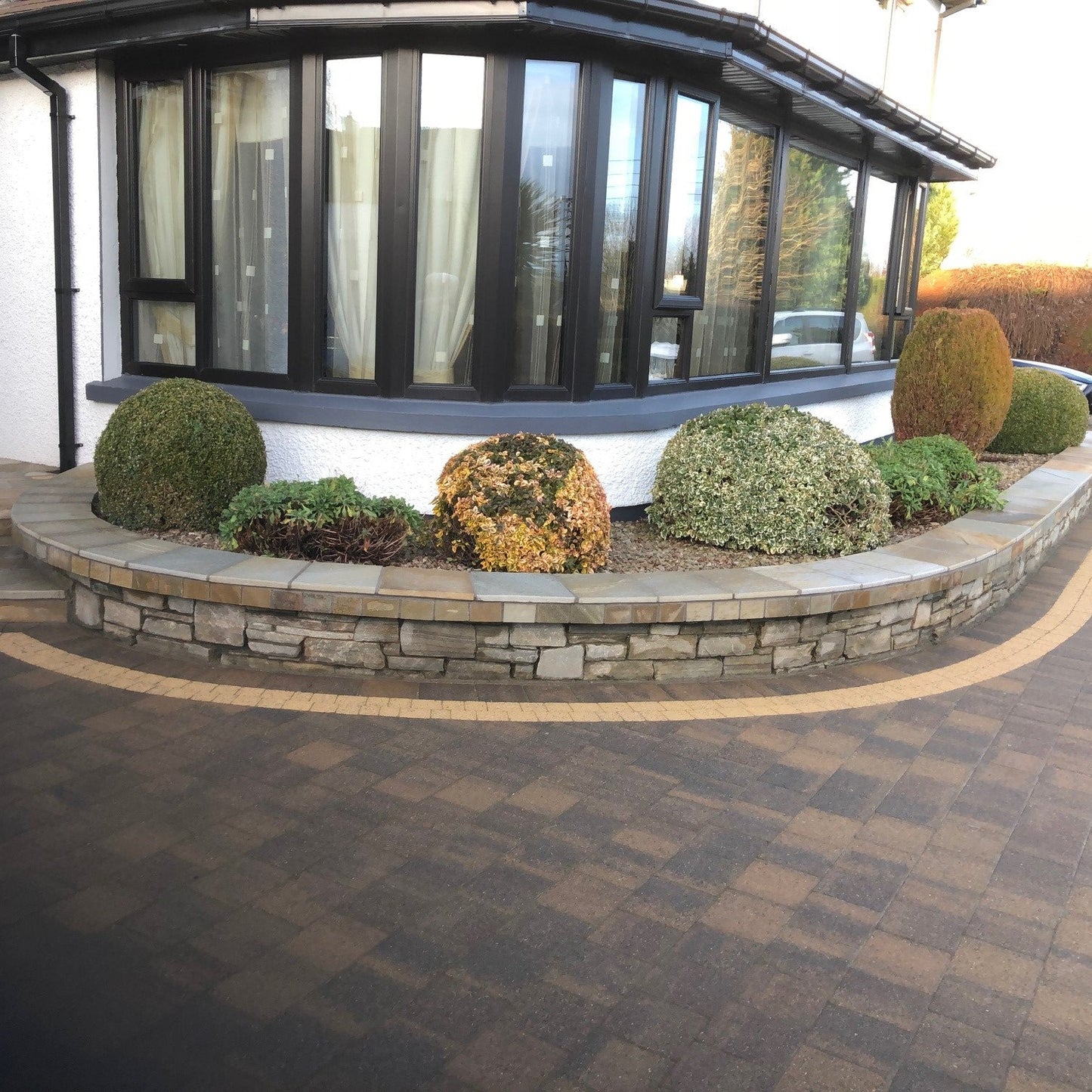 Modern house exterior with a curved raised planter wall completed with Donegal Quartzite Wall Capping.