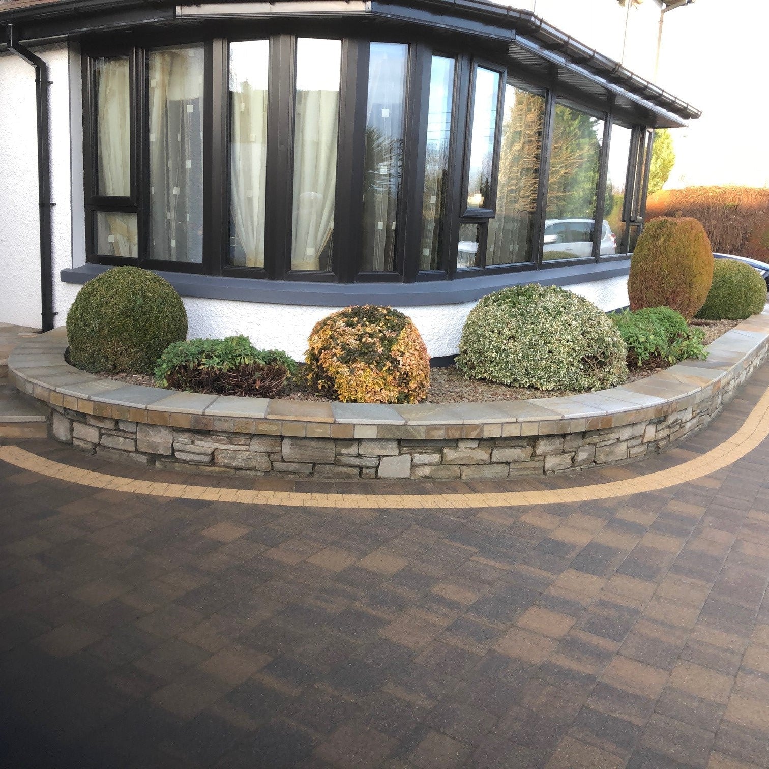 Modern house exterior with a curved raised planter wall completed with Donegal Quartzite Wall Capping.
