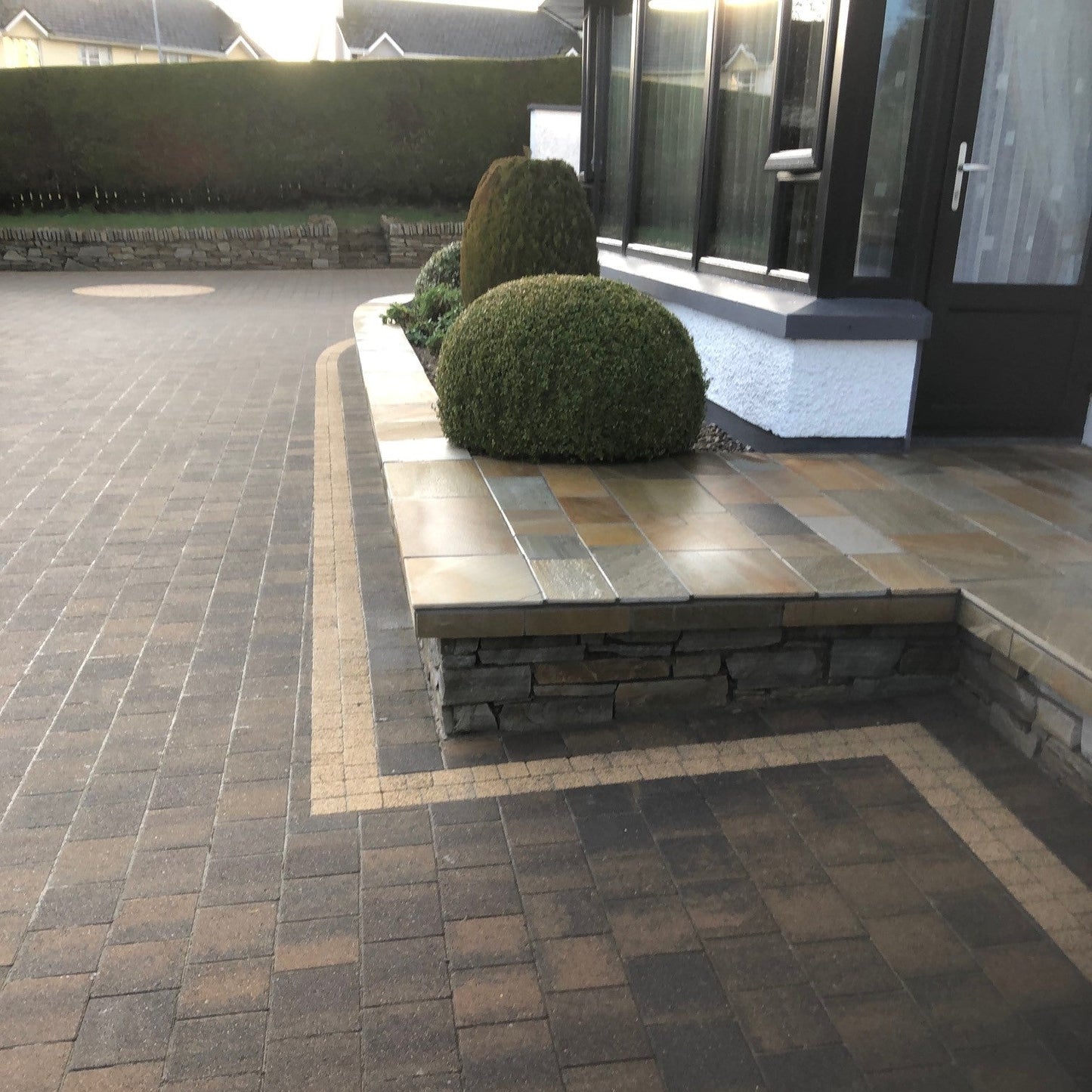 Paved patio area with landscaped bushes. Patio area completed with Donegal Quartzite Wall Capping. 
