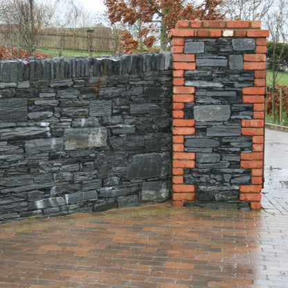 Brick and stone wall with a pathway leading to it. Stone is Donegal Slate Rubble. 