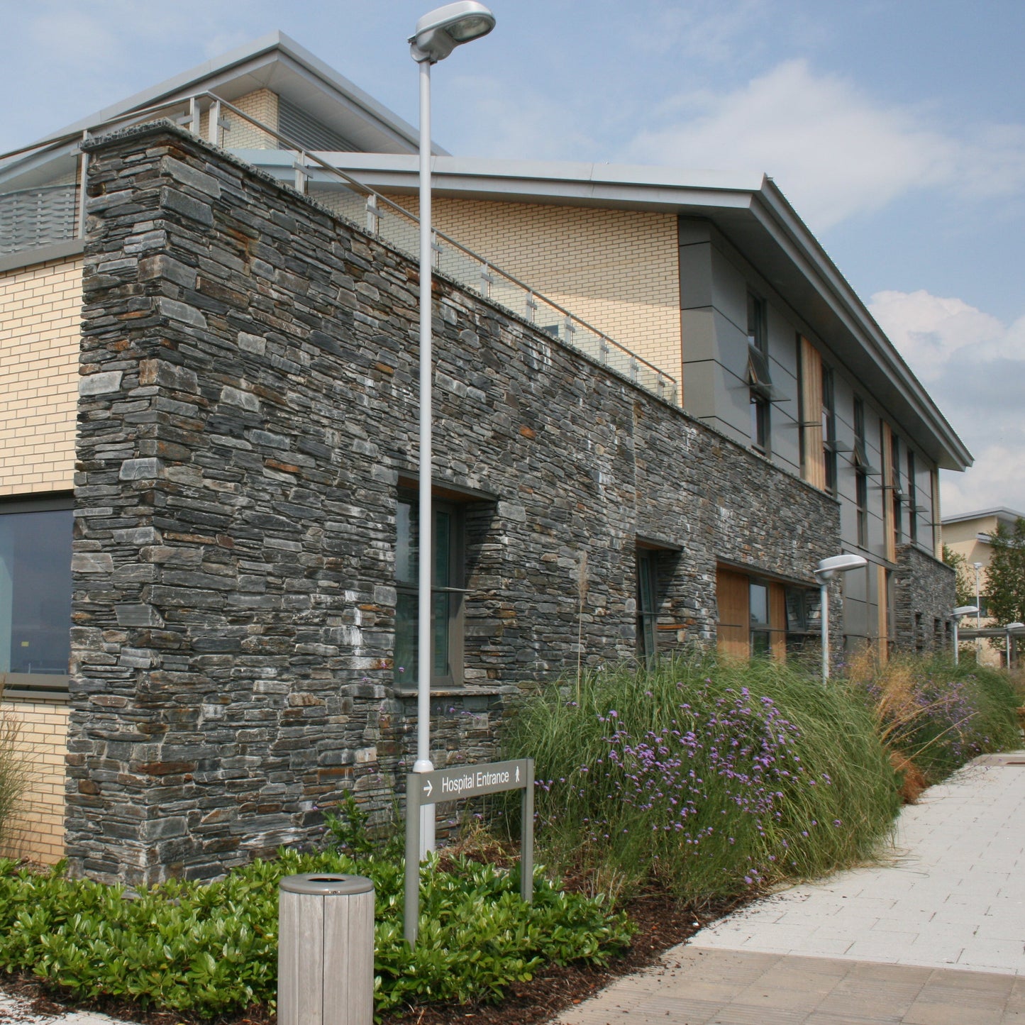 Modern building with stone facade in Donegal Slate Rubble and glass windows on a clear day