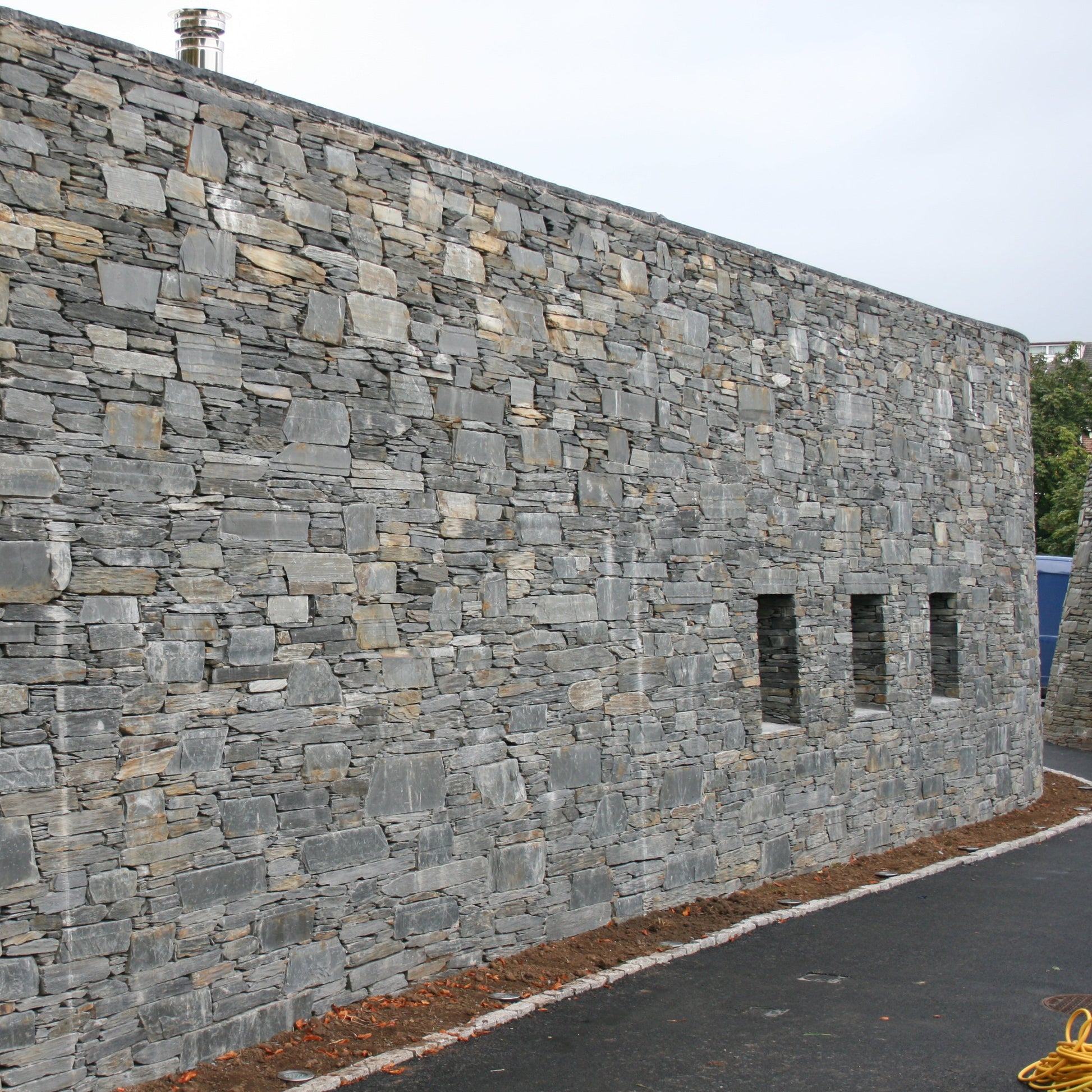 Stone building in Donegal Slate Rubble with a road in front on a cloudy day
