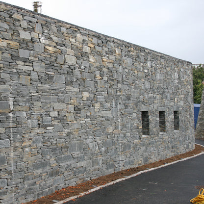 Stone building in Donegal Slate Rubble with a road in front on a cloudy day