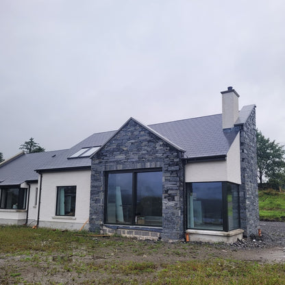 Modern house with Donegal Slate Rubble stone façade on a cloudy day