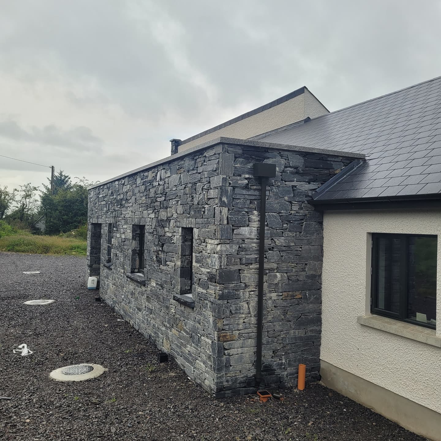 Modern house with stone facade in Donegal Slate Rubble and white exterior wall.