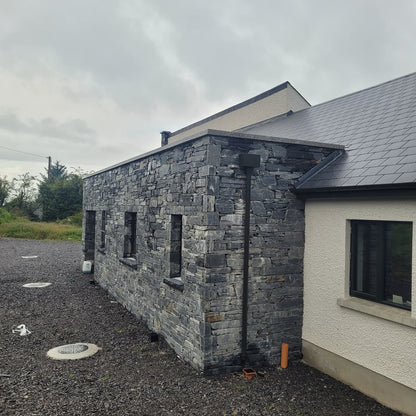 Modern house with stone facade in Donegal Slate Rubble and white exterior wall.