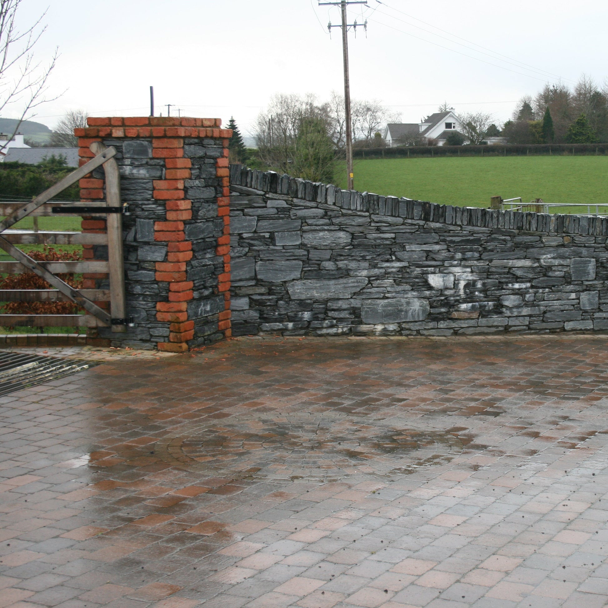 Boundary wall with a wooden gate completed in Donegal Slate Rubble and red brick. 
