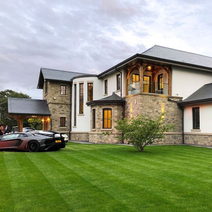 Large contemporary house with stonework showcasing Dunhill Blend Sandstone Machined.