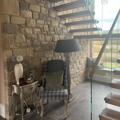 An internal wall of a building featuring Dunhill Blend Sandstone with a tumbled finish, displaying golden brown, beige, and blue tones.