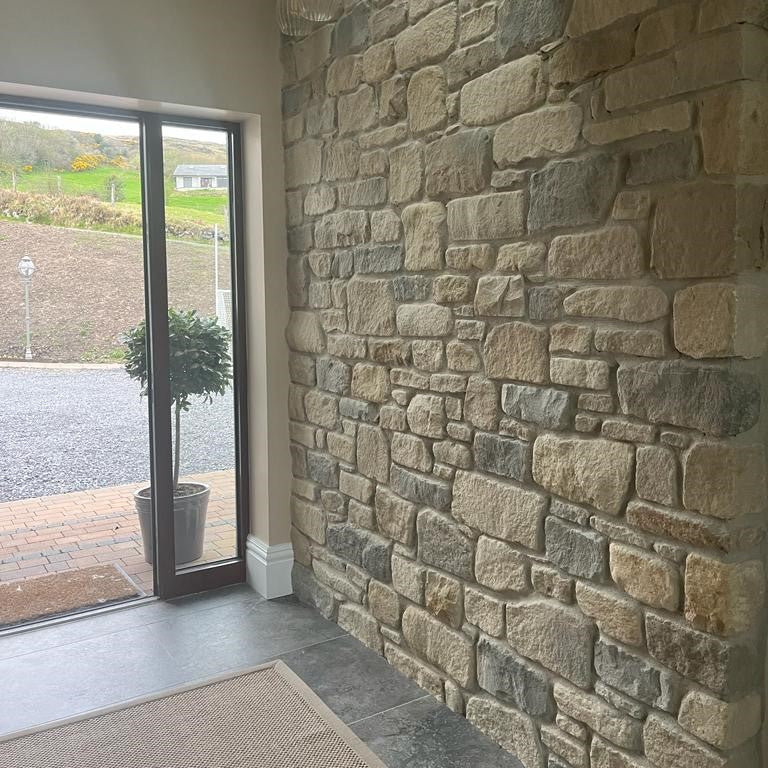 An internal wall of a building featuring Dunhill Blend Sandstone with a tumbled finish, displaying golden brown, beige, and blue tones at the entrance doorway.