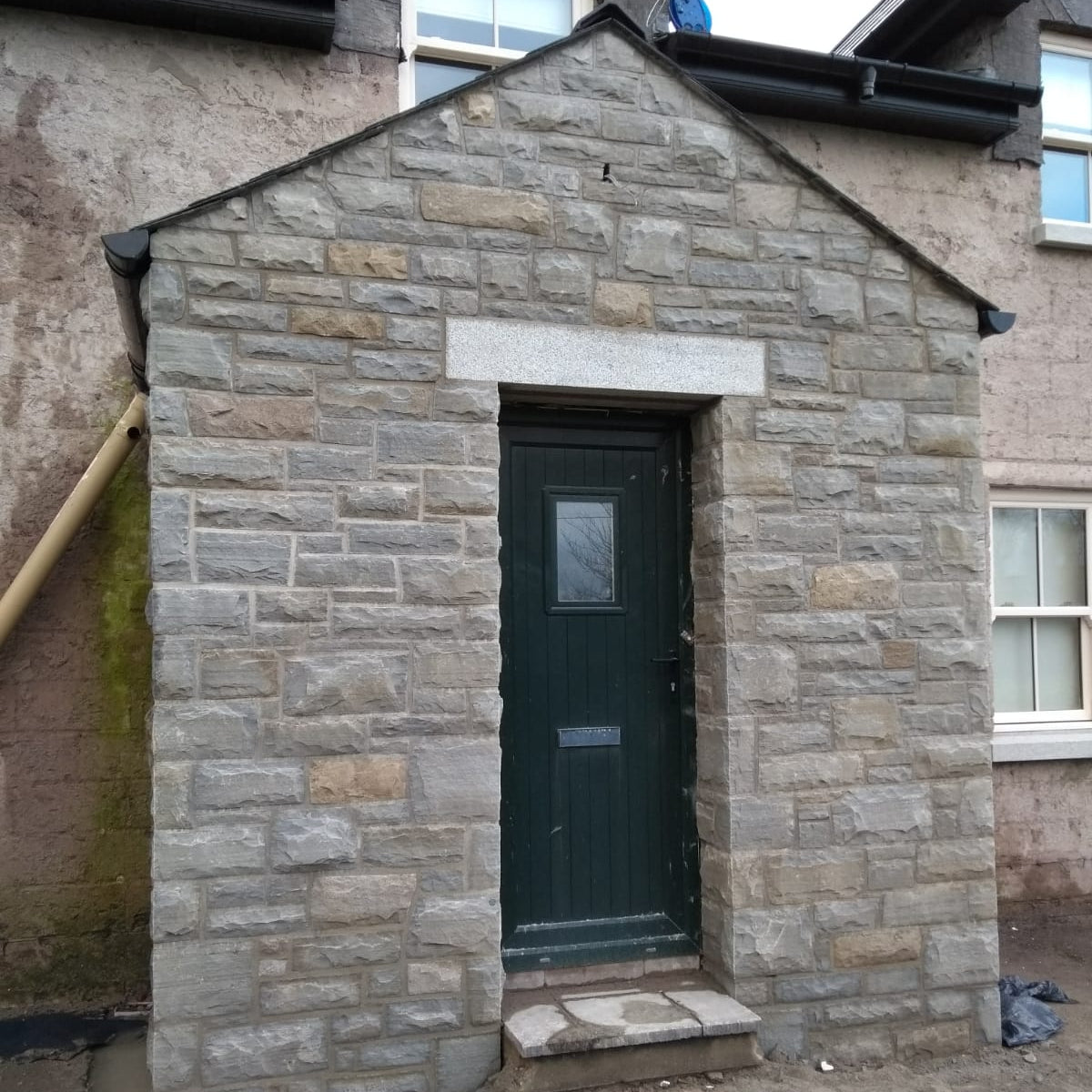 Small stone porch with a green door. Stone is Dust Grey Sandstone. 