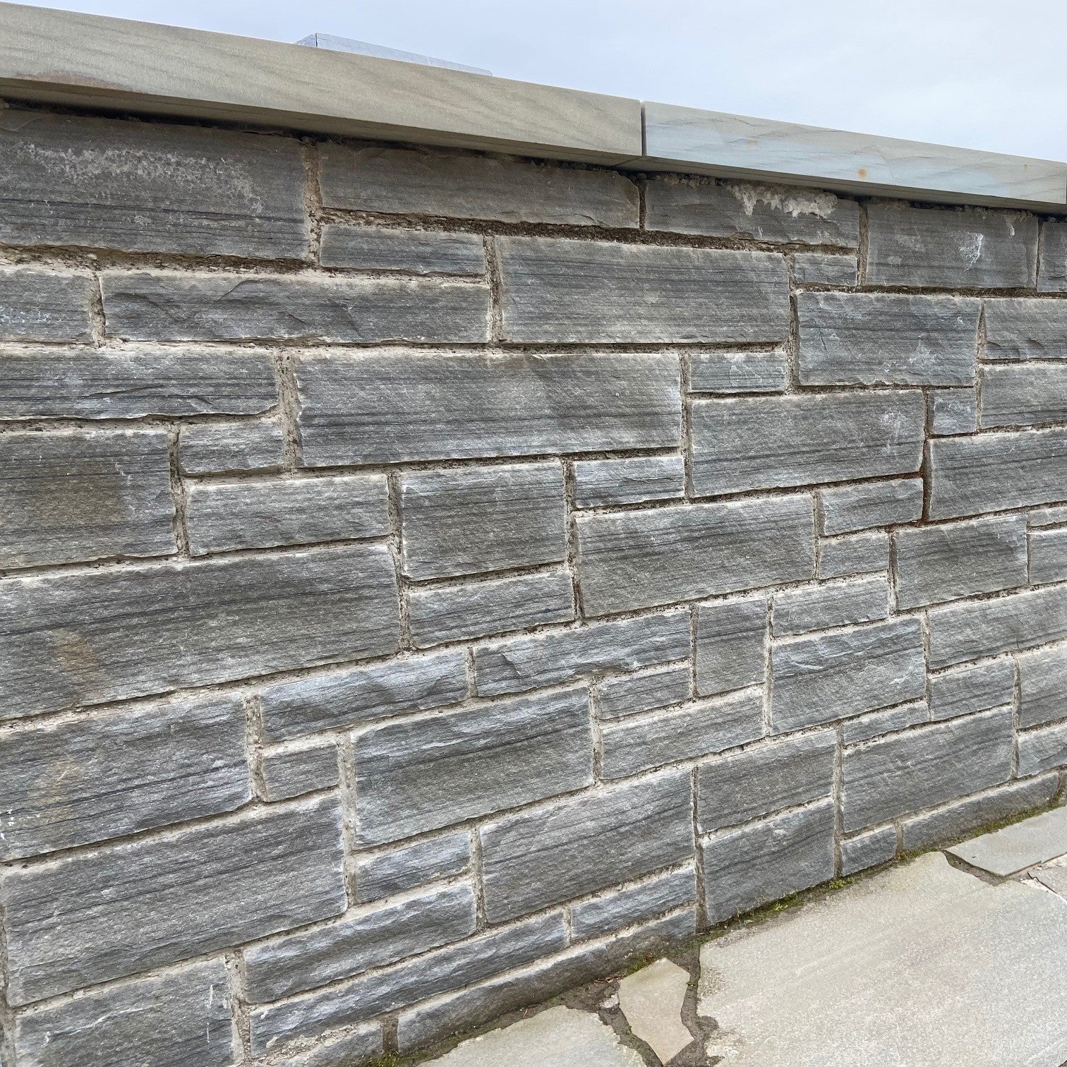 Gray stone wall in Dust Grey Sandstone with a clear sky background