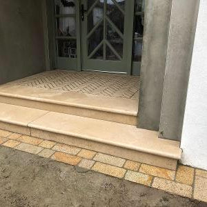 Set of stone steps leading up to a door with a patterned floor.