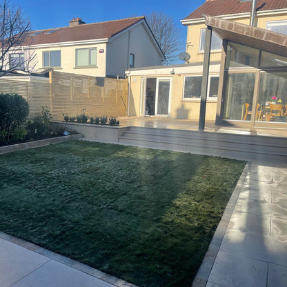 Modern house extension with patio area leading down to garden. Grass is bordered by Egyptian Limestone Paving Setts. 