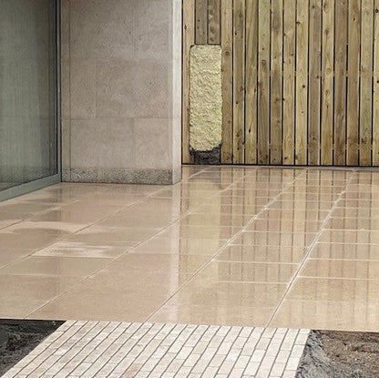Egyptian Limestone patio area with a concrete wall and wooden panel in the background. 