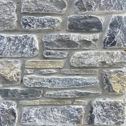A close-up image of a wall constructed from Fieldstone Blend stones, showing a variety of grey and brown shades with a tumbled finish.