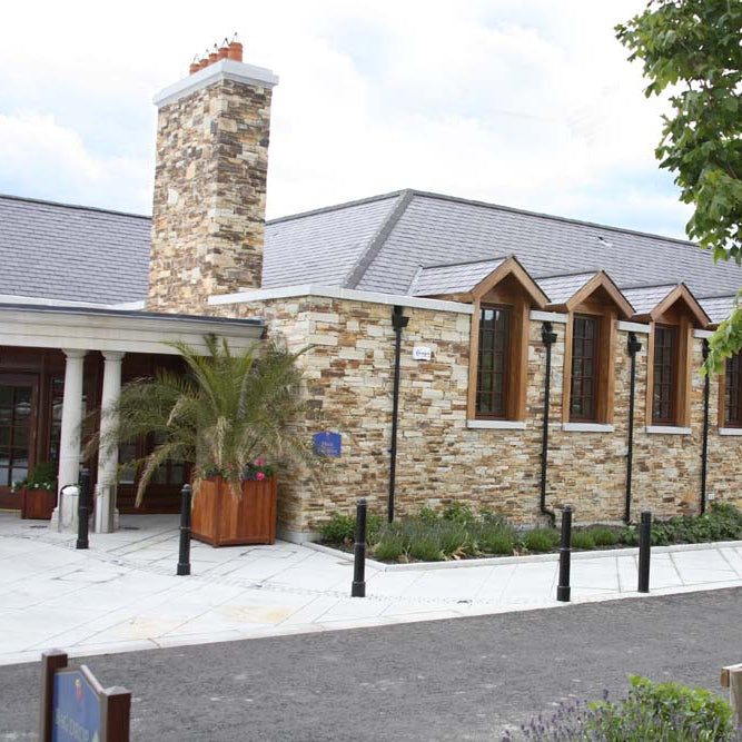 Building with stone facade completed in Gold Donegal Quartzite Machined walling stone and wooden accents on a cloudy day.