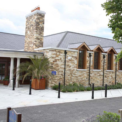 Building with stone facade completed in Gold Donegal Quartzite Machined walling stone and wooden accents on a cloudy day.