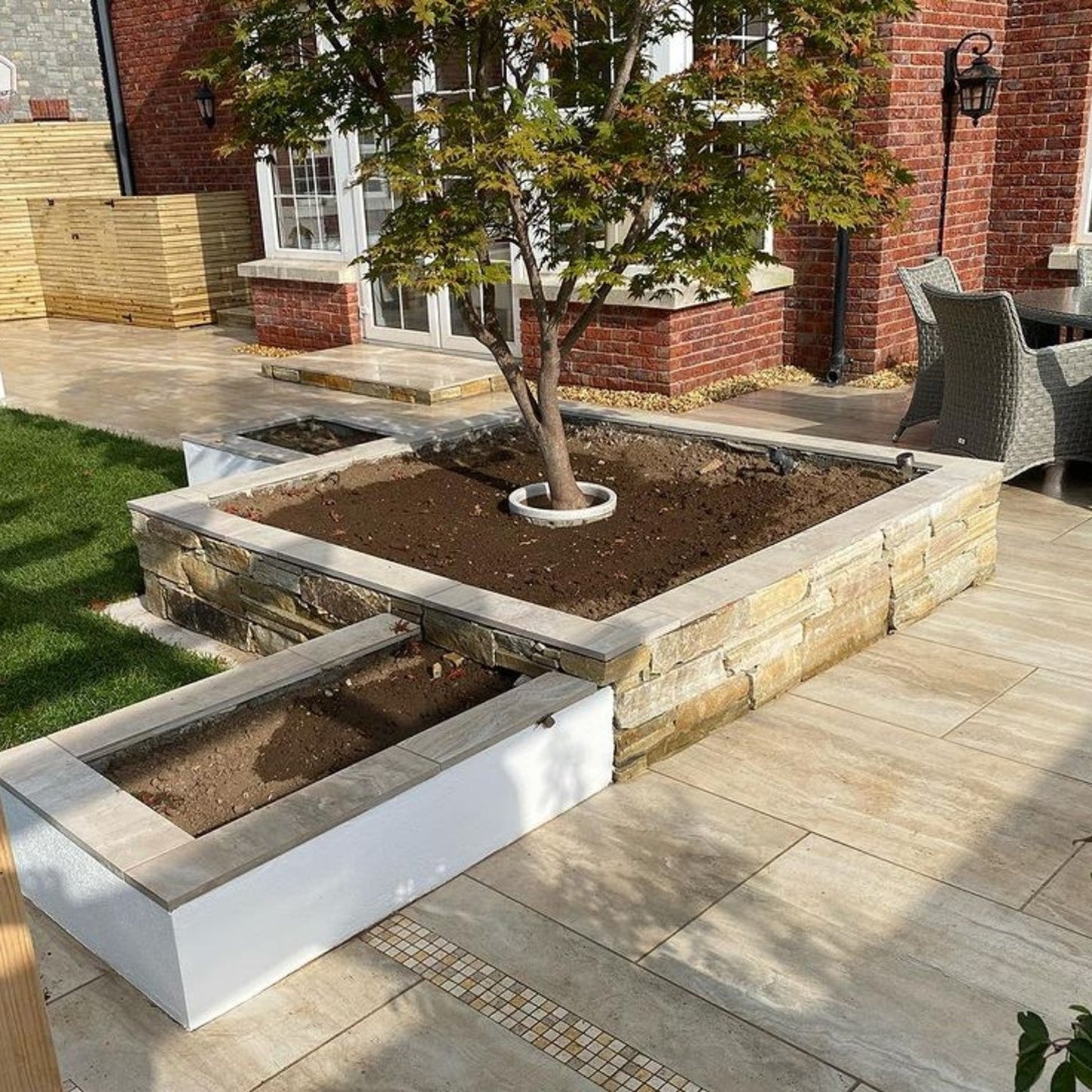 Landscaping wall surrounding a tree in a patio area completed using Gold Donegal Quartzite Stoneer Cladding. 