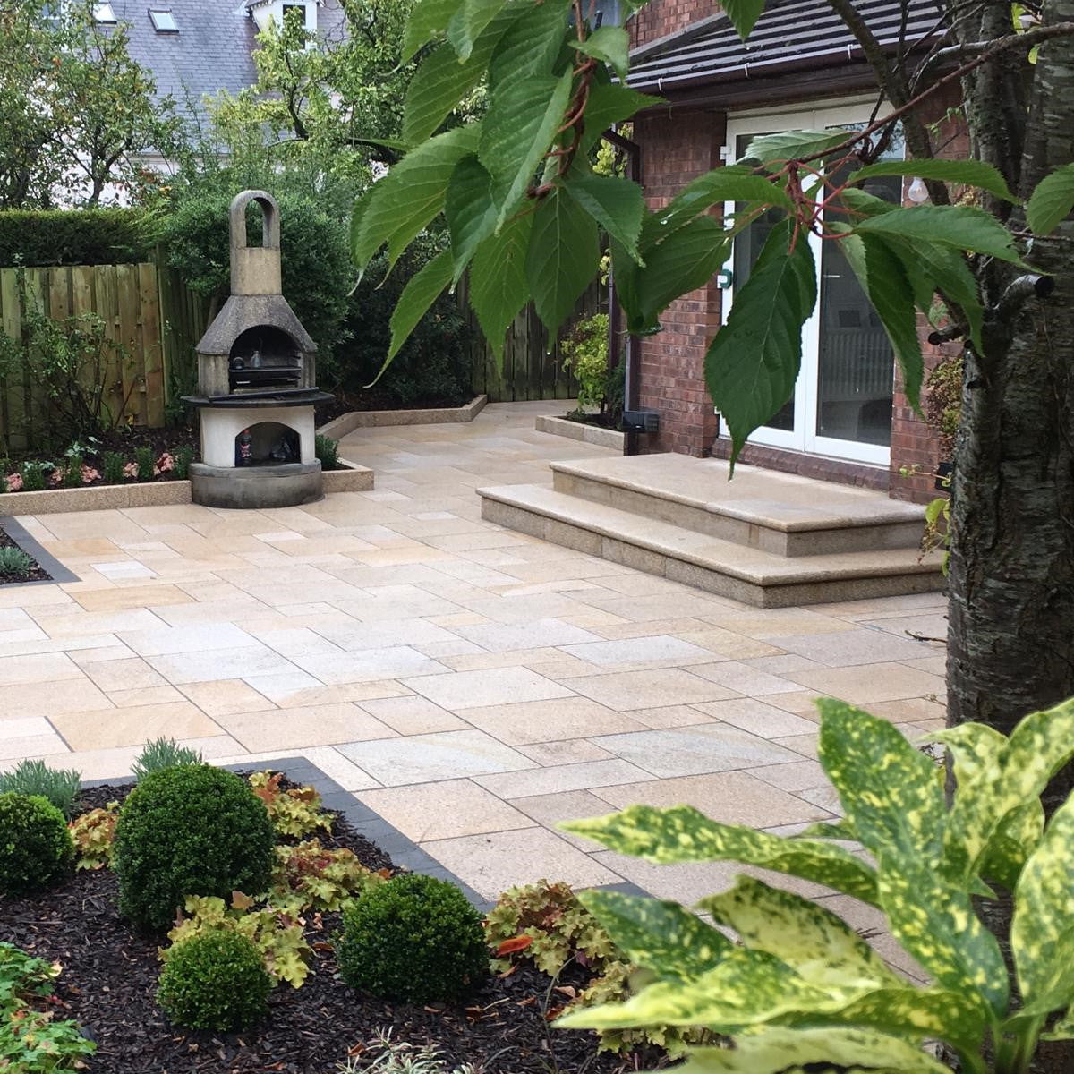 Backyard patio with outdoor fireplace, Gold Granite Steps and paving, and garden beds.