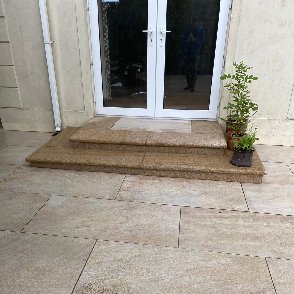 Porcelain patio area with a glass door and plants. Steps completed using Gold Granite Step packs. 