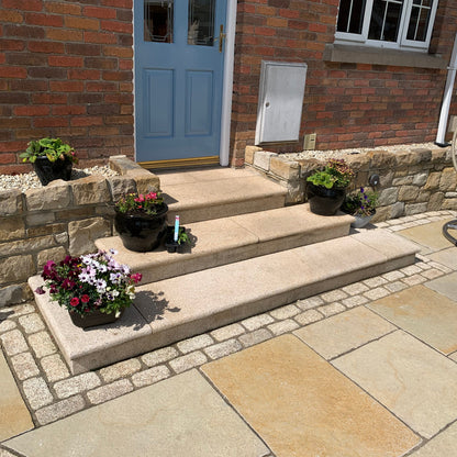 Gold Granite Steps and cobbles leading up to a blue door on a red brick house. 
