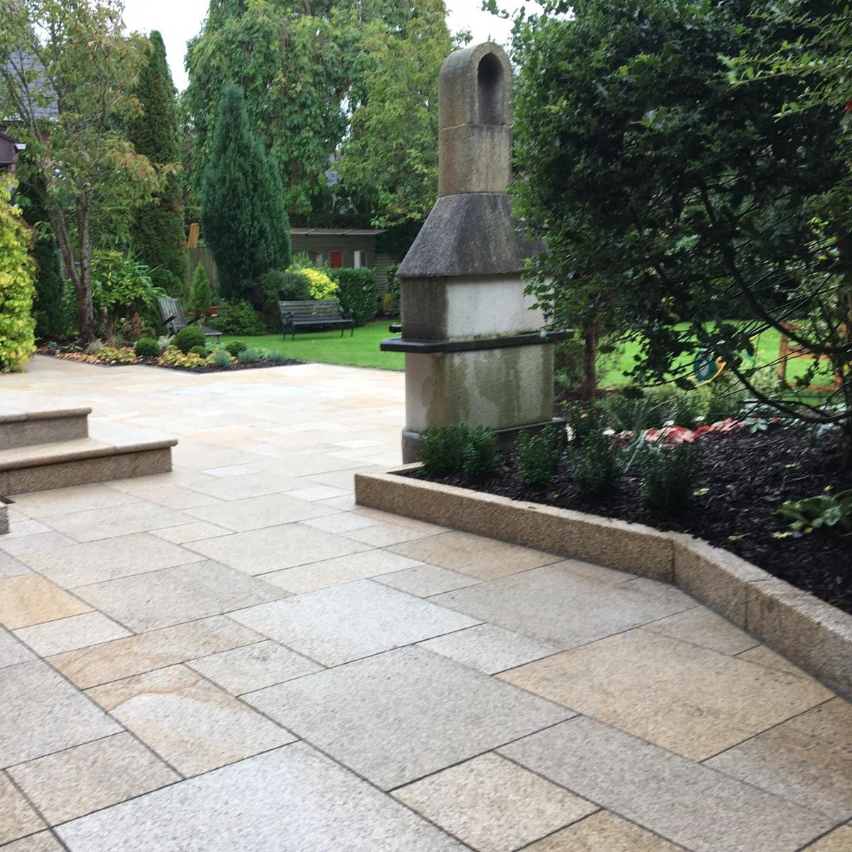 Patio area with Gold Granite Kerbing with garden and trees in the background.