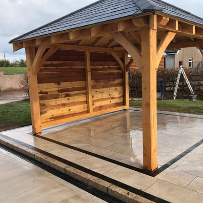 Wooden patio pergola with featuring porcelain, black cobbles and gold granite kerbing. 