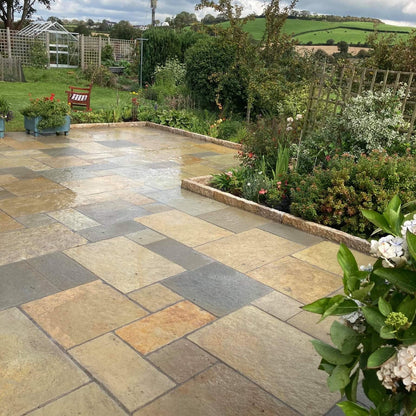 Paved patio area with garden and greenery under a cloudy sky. Patio border completed using Gold Granite Kerbs with a pineapple finish. 