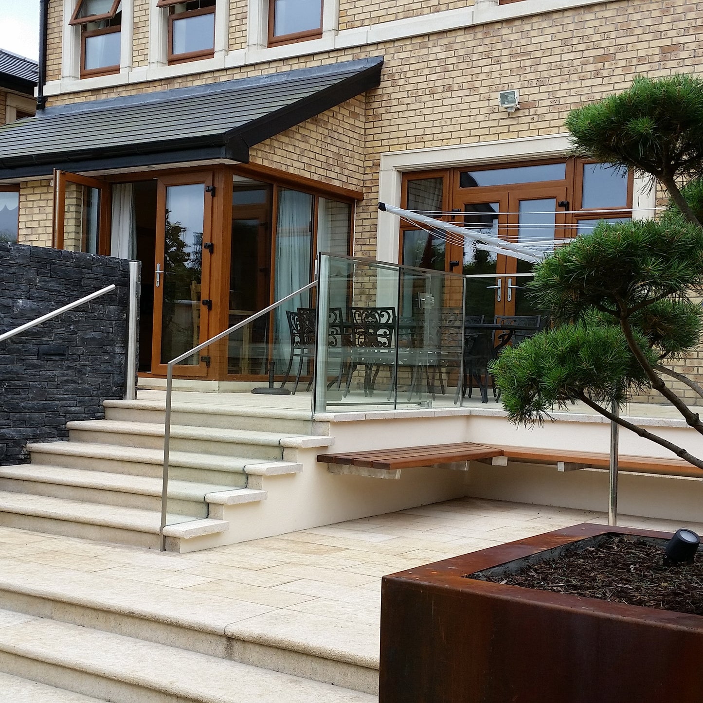 Brick house with natural stone steps and patio area completed using Gold Granite Paving in 600 x 300mm size. 