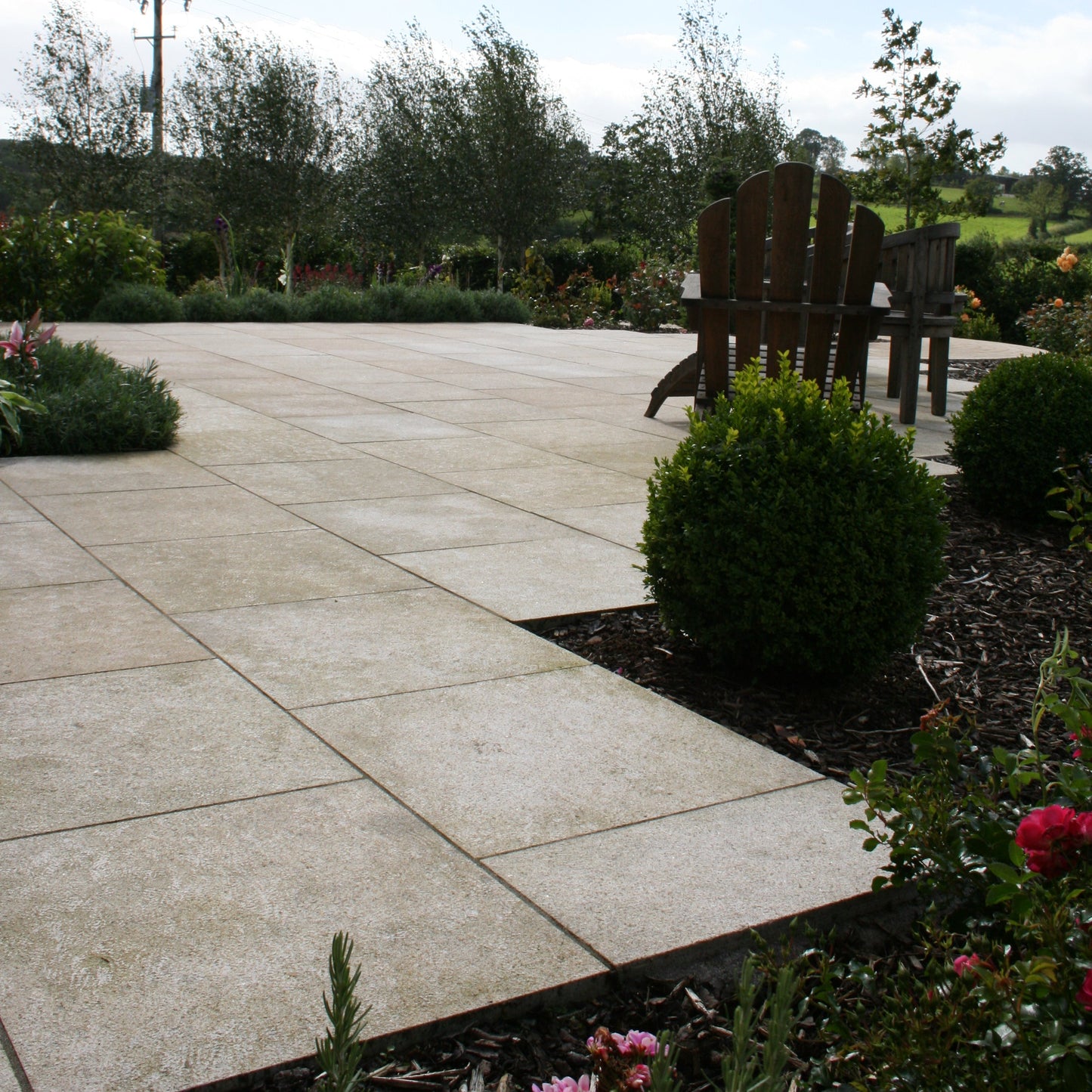Gold Granite paving featuring 600 x 600mm size paving slabs. Patio surrounded by planting. 