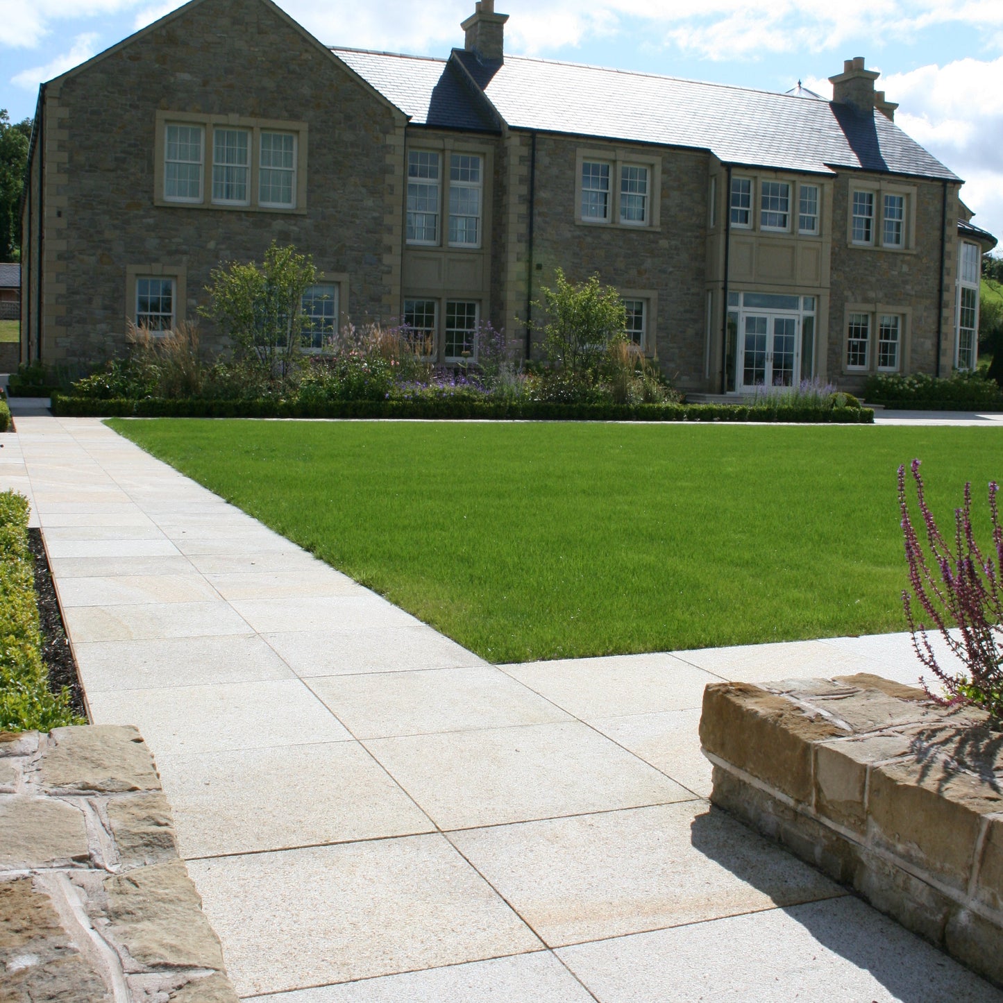 Large stone house with well maintained garden and natural stone pathways in Gold Granite Paving in 600 x 600mm size. 
