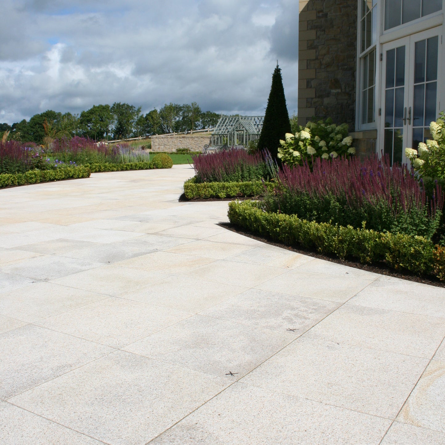Gold Granite Patio Paving in 600 x 600mm size surrounded by beautiful planting. 
