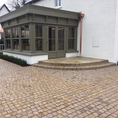 Modern house and sunroom leading out to Patio area featuring Gold Granite Paving Cobbles in 100 x 100mm size. 