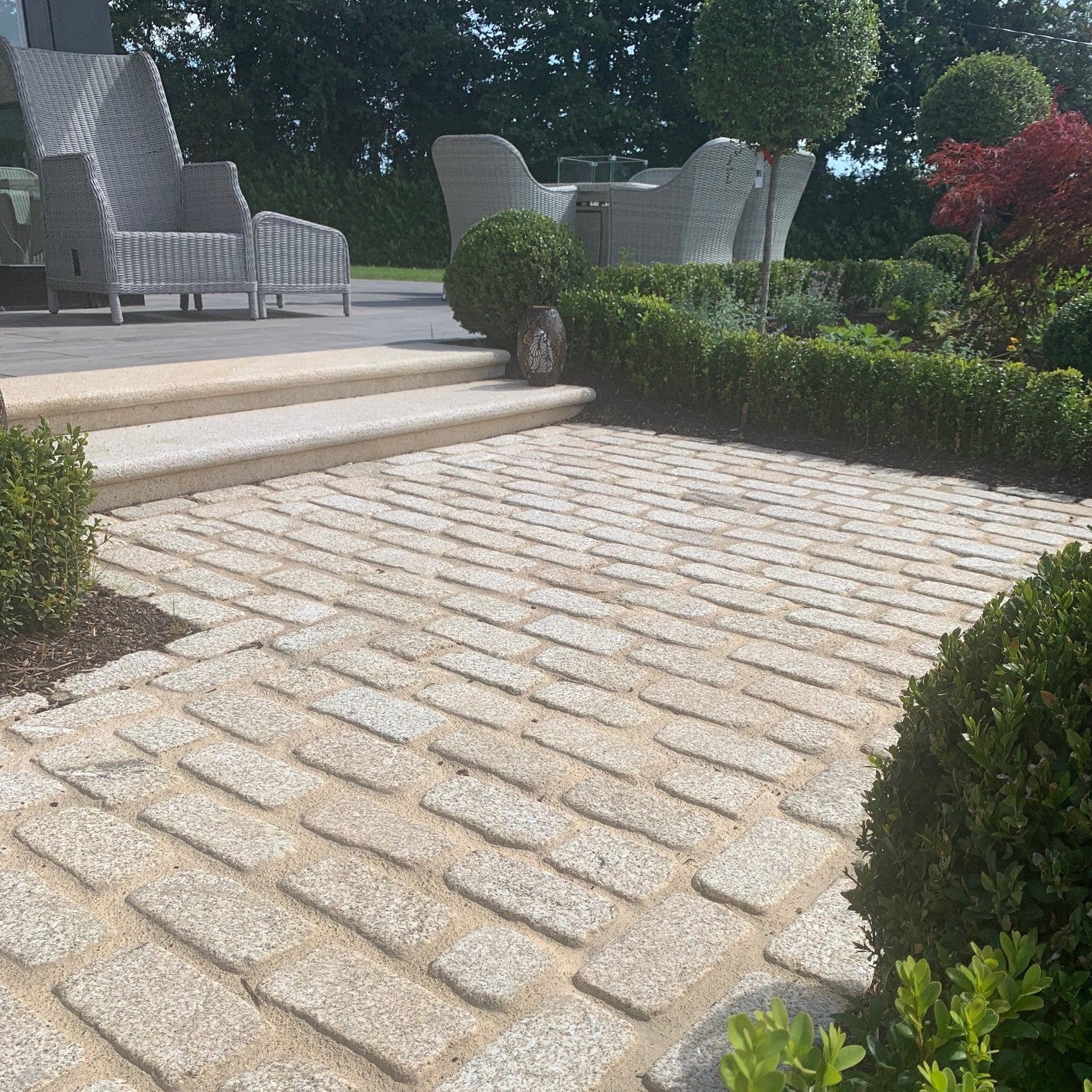 Pathway leading to patio area featuring lightly tumbled gold granite cobbles and gold granite steps. 