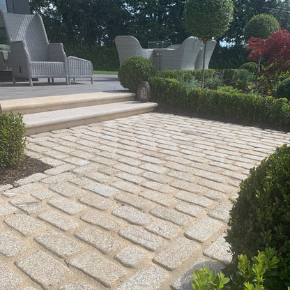 Pathway leading to patio area featuring lightly tumbled gold granite cobbles and gold granite steps. 