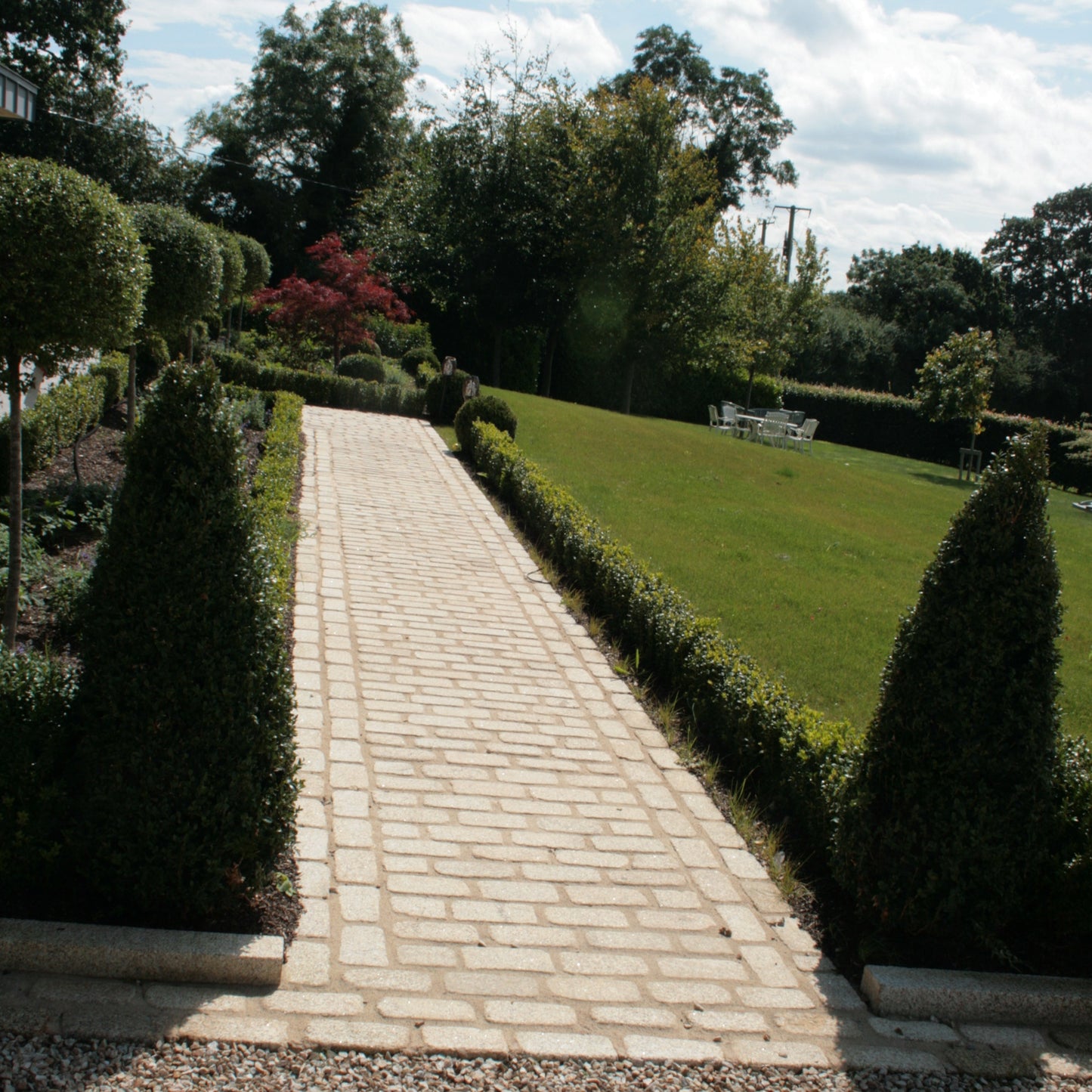 Pathway with hedging on either side featuring lightly tumbled Gold Granite Paving Cobbles in  200 x 100mm size. 