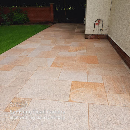 Patio area to the side of a house finished in Gold Granite Paving in mixed patio sizes. 