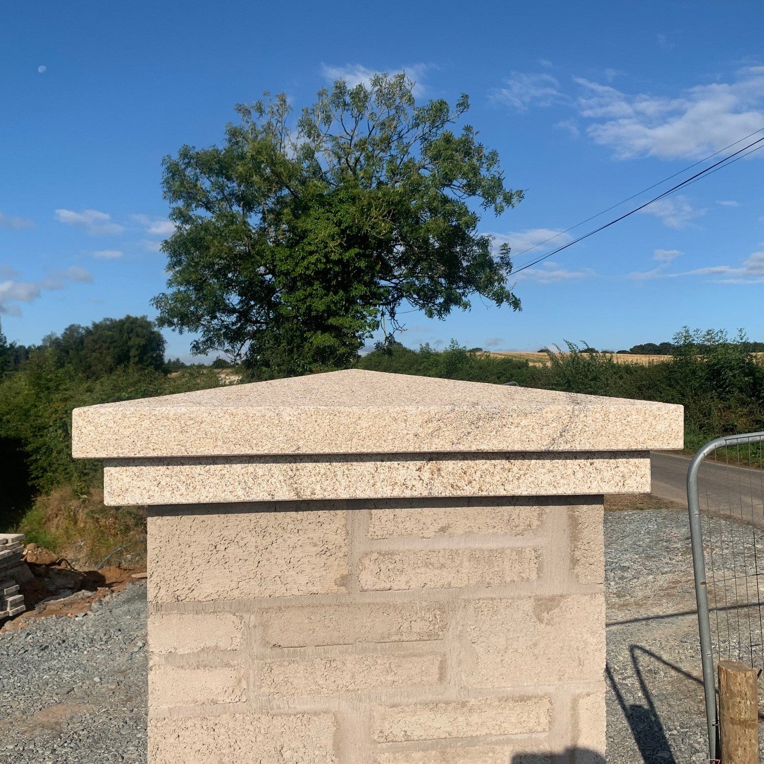 Bespoke Apex Gold Granite Pillar Cap with a blue sky in the background. 
