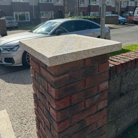 Brick pillar with a bespoke gold granite pier cap in a residential area.