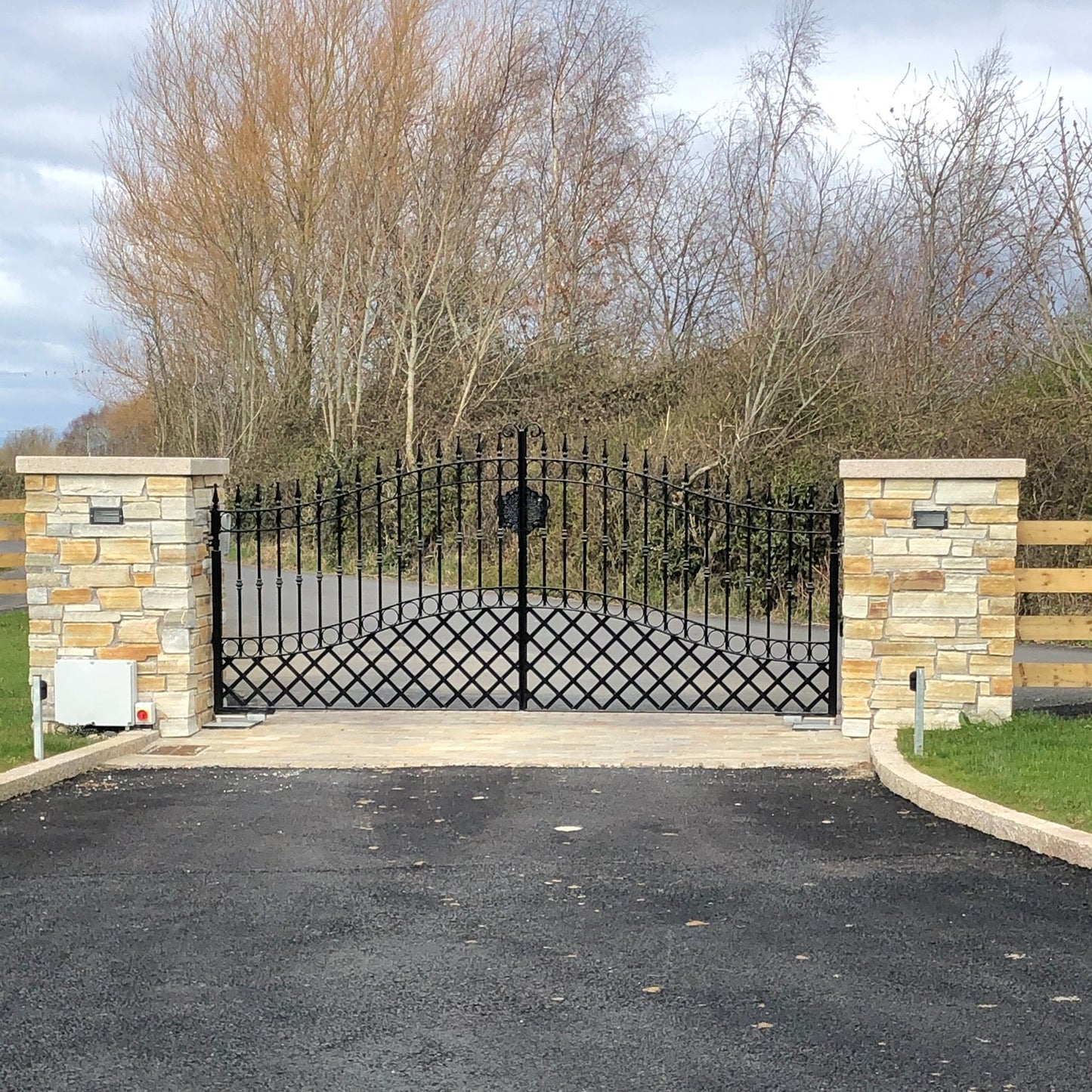 Black metal gate with stone pillars and flat bespoke gold granite pillar capping. 