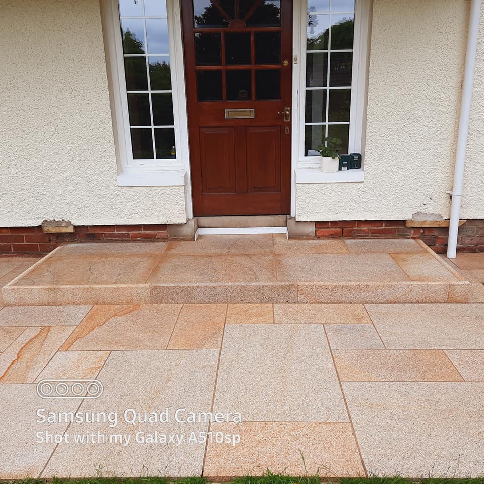 Paved pathway with step leading to a house with a wooden door. Step finished using Gold Granite Pin Kerbs. 