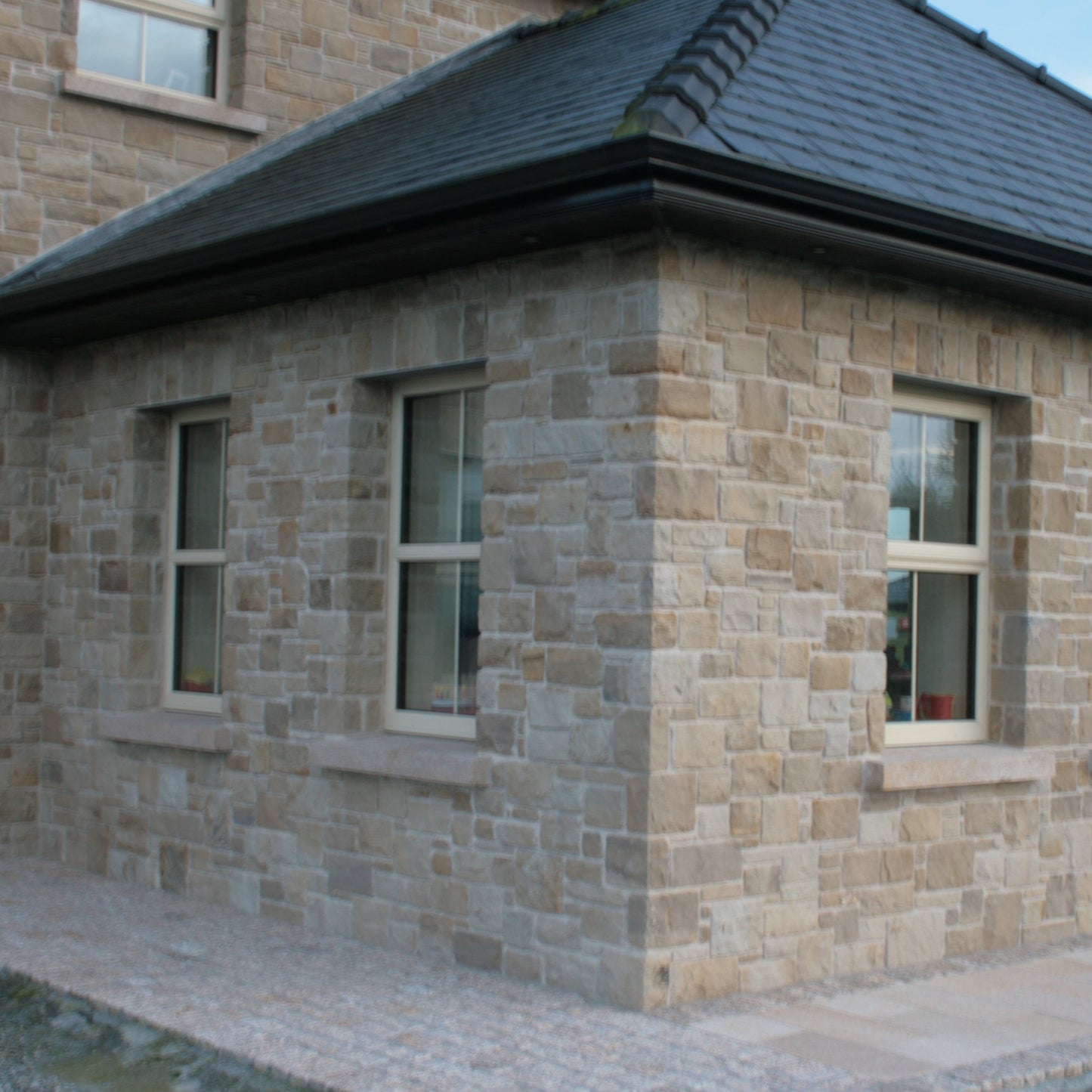 Stone building with windows and bespoke gold granite sills. 