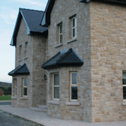 Two-story house with stone façade and bespoke Gold Granite Window Sills. 
