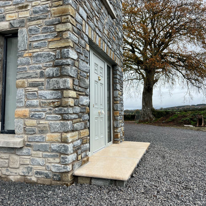 Stone building with a door and tree in the background. Gold Granite Step leading to front door. 