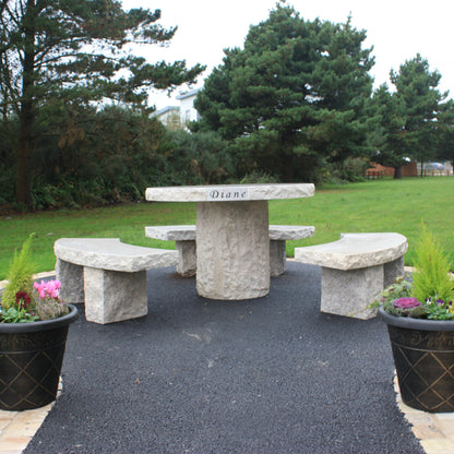 Garden with trees and Gold Granite Table & Bench Set on a tarmac area with two flower pots in the foreground. 