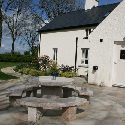 White house with patio area featuring a Gold Granite Table and Bench Set. 