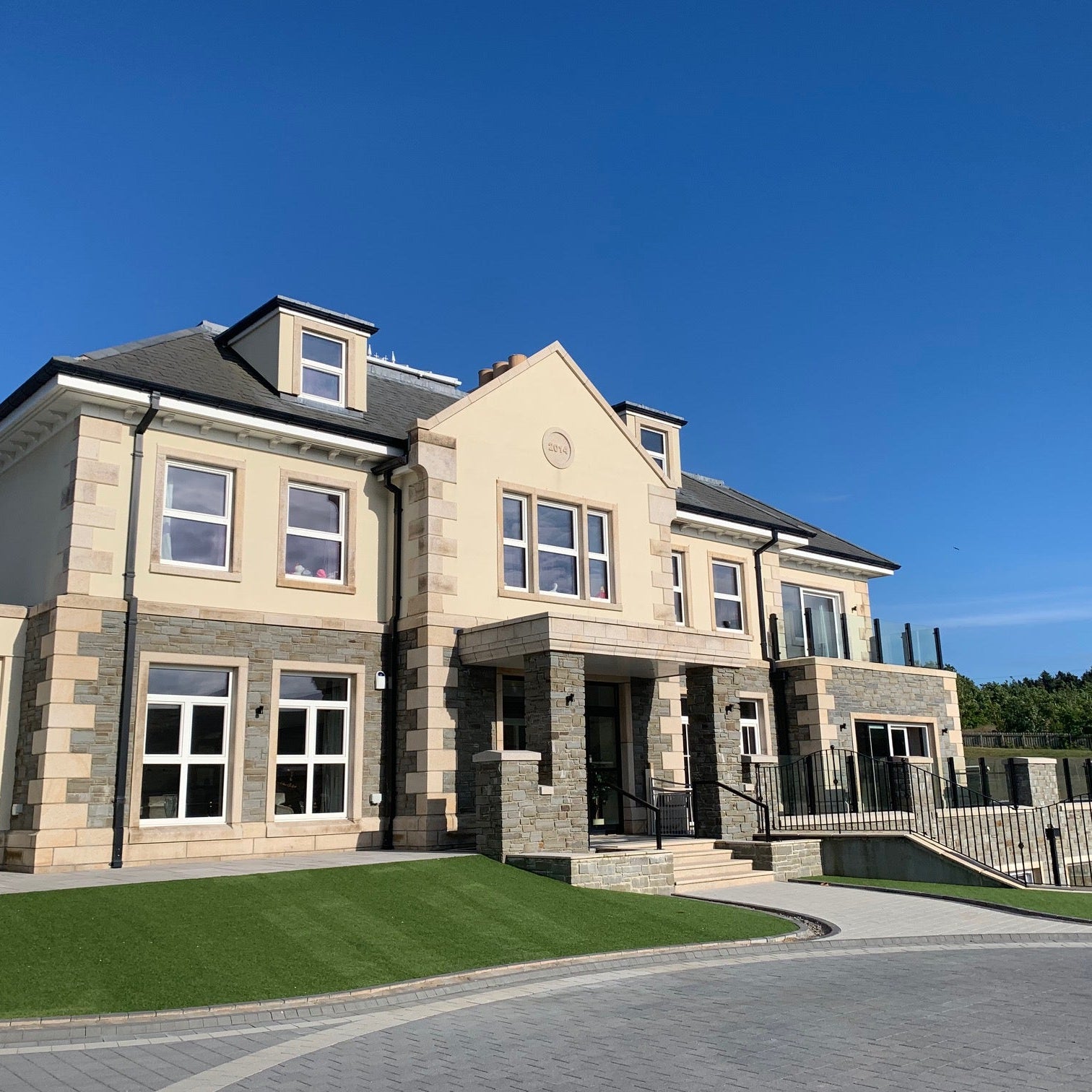 Large stone house with stone façade featuring Gold Granite Window & Door Surrounds on sunny day.
