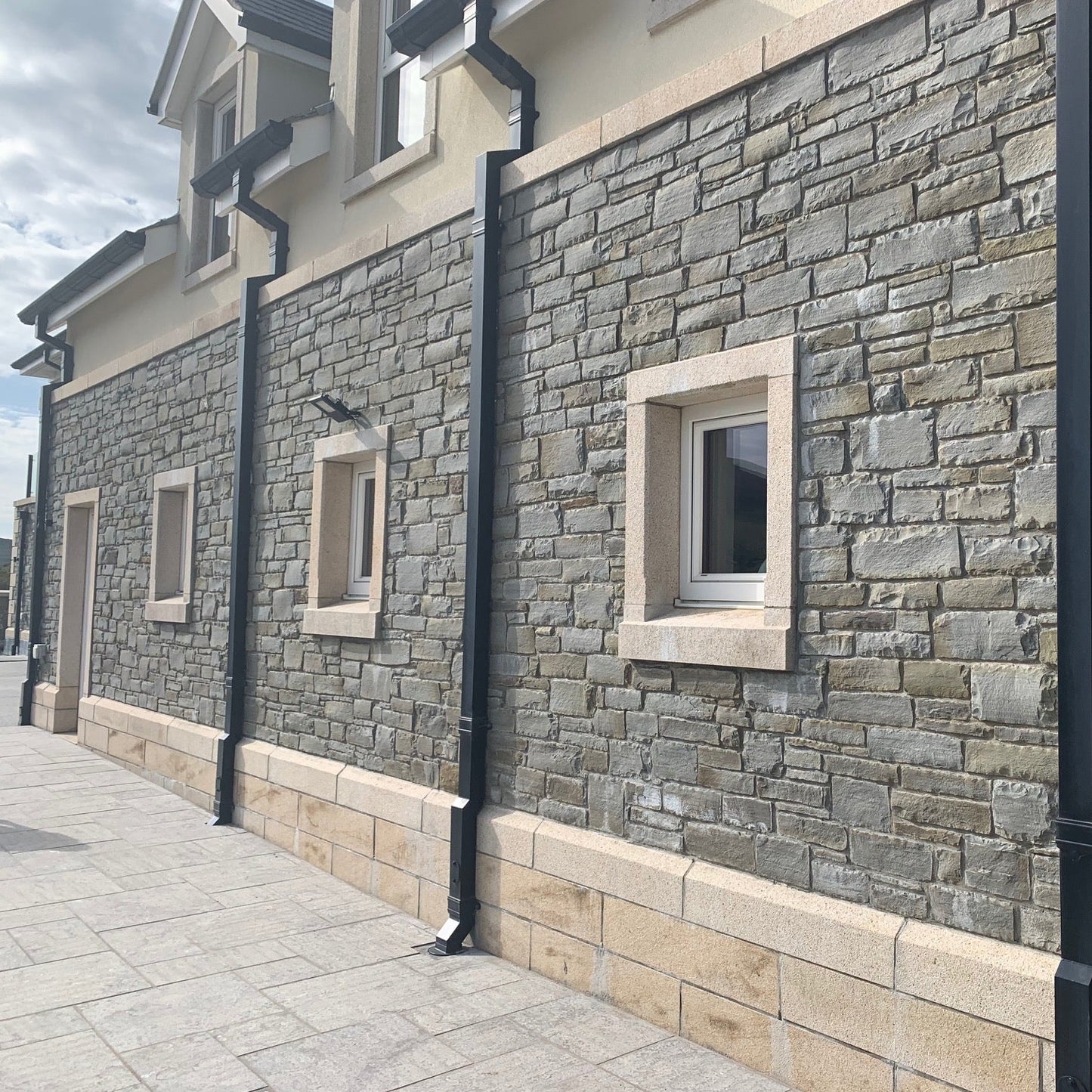 Bespoke Gold Granite Window Surrounds, Plinth and Wall Capping on stone façade. 
