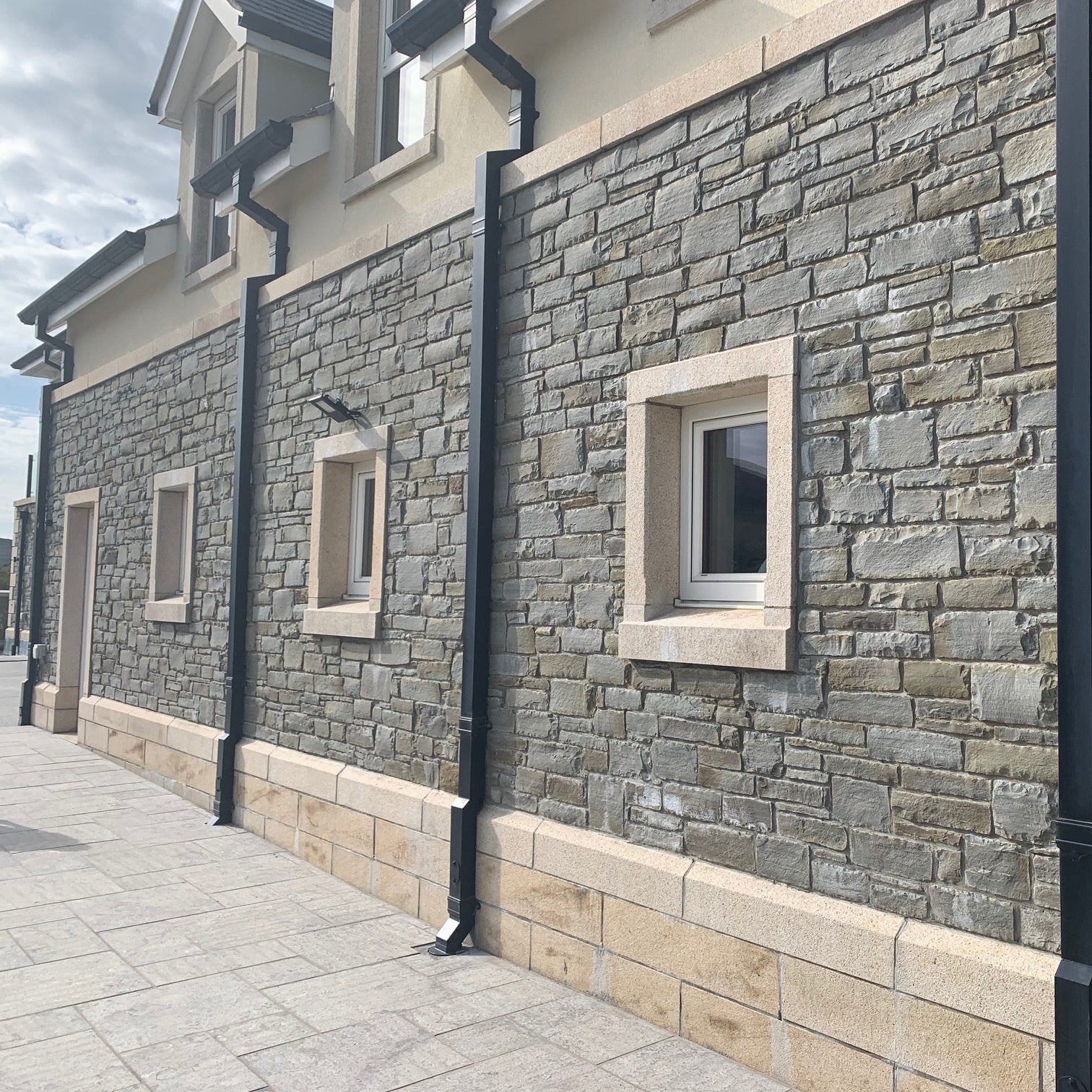 Bespoke Gold Granite Window Surrounds, Plinth and Wall Capping on stone façade. 